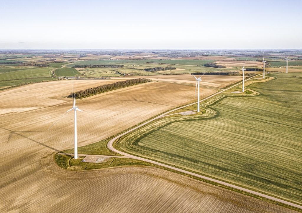 take-the-aerial-of-the-turbines-and-the-hermosous-green-fields-about-the-sharp-oranges