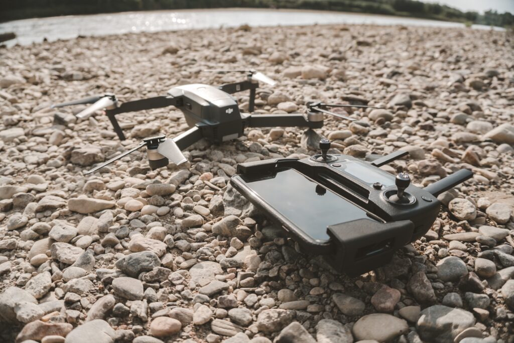 A closeup shot of a high-tech drone and its' remote control device on gray pebbles